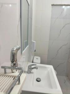 a white bathroom with a sink and a mirror at Pensão Simão & Júlia - 8 Quartos in Órgãos
