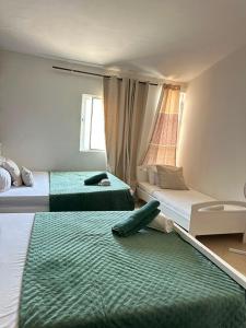 a bedroom with two beds with green sheets and a window at Pensão Simão & Júlia - 8 Quartos in Órgãos