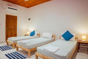 two beds in a room with blue pillows at Neem Tree Boutique Resort in Serukele