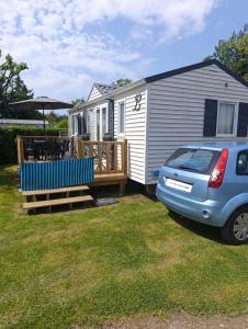 a tiny caravan with a deck and a car parked in front at vent de liberté 80 camping les peupliers in Vironchaux