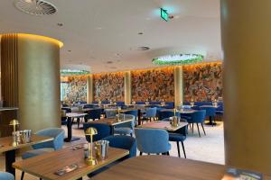 a dining room with tables and blue chairs at TRYP Badhotel The Hague Scheveningen BRAND NEW in Scheveningen