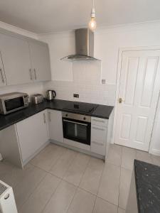 a kitchen with white cabinets and a black counter top at Brennan stays contractor professional Friendly in Liverpool
