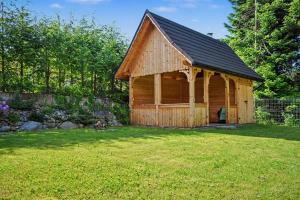 a log cabin with a black roof in a yard at Apartamenty Widokowe Pod Lasem in Kościelisko