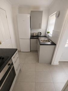 a white kitchen with a sink and a refrigerator at Brennan stays contractor professional Friendly in Liverpool