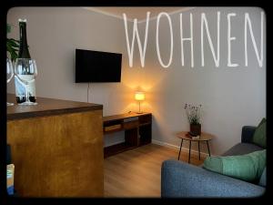 a living room with a tv on a wall with a sign at Gemütliches Apartment mit Moselblick in Reil