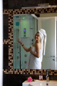 a woman standing in front of a bathroom mirror at Hotel C'era Una Volta in Castiglione della Pescaia +37 photos