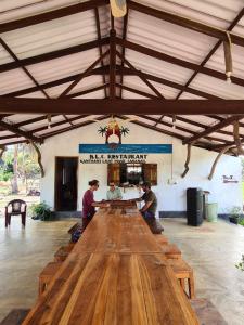 three people sitting around a large wooden table at Kanthans Lighthouse Cabanas in Komari