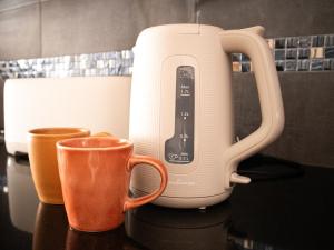 a coffee maker and two cups on a counter at Casa 4 Peixes in Leiria
