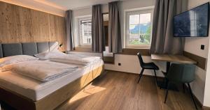 a bedroom with a bed and a tv and a chair at Marktplatz Apartments Lofer in Lofer