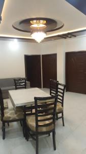 a dining room with a table and chairs and a chandelier at Galyat Apartments in Abbottabad