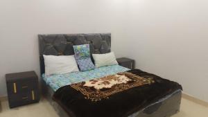 a bedroom with a bed with a headboard and pillows at Galyat Apartments in Abbottabad