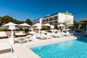 a pool with chairs and umbrellas next to a hotel at Can Miquel in L'Escala