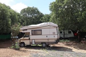 a camper van parked in a field next to trees at קרוואן עם חיוך in Odem