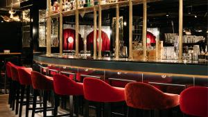eine Reihe roter Stühle an einer Bar in der Unterkunft Ruby Mimi Hotel Zurich by IHG in Zürich