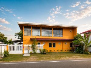 a yellow house with a white fence at Gloria's Home Stay in Oslob