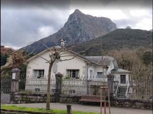 a white house with a fence and a mountain at Casa con bosque en Cantabria in Ramales de la Victoria