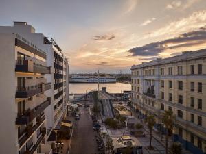 eine Stadtstraße mit Gebäuden und einem Boot im Wasser in der Unterkunft Mural Piraeus Hotel in Piräus