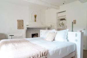 a white bedroom with a white bed and a fireplace at La Bastide du Mourre - Fontenille Collection in Oppède
