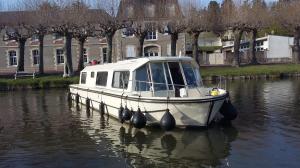 a boat is docked in the water on a river at Rem'Ann boat in Briare