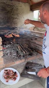 a man cooking food on a grill with a plate of food at Castaños - Casal do Conde in Caldas de Reis