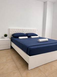 a bed with blue sheets and pillows in a room at Cozy Apartment Astiri in Tirana