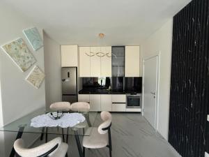 a white kitchen with a glass table and chairs at Shengjin Apartament 5 M in Shëngjin