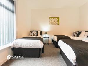 two beds in a room with a window at Modern 2-Bedroom Home in Bolton Spacious & Comfortable in Bolton