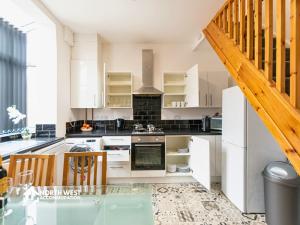 a kitchen with white cabinets and a wooden staircase at Modern 2-Bedroom Home in Bolton Spacious & Comfortable in Bolton