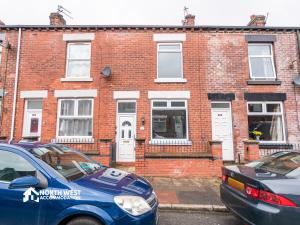 two cars parked in front of a brick building at Modern 2-Bedroom Home in Bolton Spacious & Comfortable in Bolton