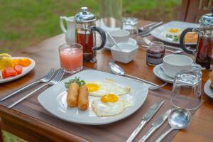 a wooden table with plates of breakfast food on it at Neem Tree Boutique Resort in Serukele