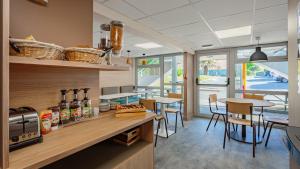 a kitchen with wooden counter and tables and chairs at Premiere Classe Lyon Ouest - Tassin in Tassin-la-Demi-Lune