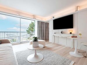 a living room with a tv and a large window at Bel Hôtel Oléron Thalasso & Spa - MGallery Collection in Saint-Trojan-les-Bains