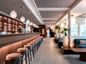 a bar in a restaurant with stools at Bel Hôtel Oléron Thalasso & Spa - MGallery Collection in Saint-Trojan-les-Bains