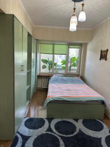 a bedroom with a bed and a window and a rug at Bishkek Apartment Central in Bishkek