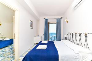 a bedroom with a bed with a blue blanket and a window at Terrazza di Rosa - sea view in Praiano