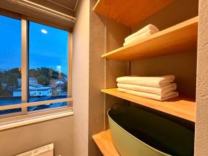 a bathroom with a window and a shelf with towels at Grand Opening SORA Yunokawa Penthouse in Hakodate +52 photos