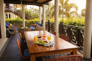 a wooden table with a plate of food and glasses of orange juice at POCO POCO Villa - Poolside Golf & Beachfront Resort in Dorp Sint Michiel