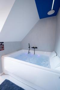 a bath tub with a faucet in a room at Capsule Santorini - balneo - Sauna - Switch 2 in Limelette +63 photos