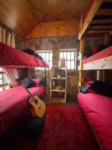 a room with two bunk beds with a guitar in it at Refugio de Montaña Placaroja in San José de Maipo