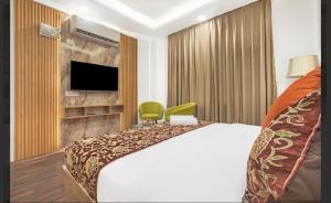 a hotel room with a bed and a flat screen tv at Hotel Seven Hill Star in Srinagar