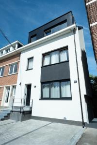 a white house with black windows on a street at Capsule Santorini - balneo - Sauna - Switch 2 in Limelette