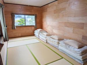 a room with three beds in a room with a window at おかえりヒュッテ in Komagane