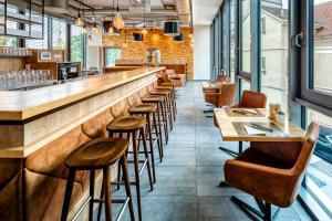 a row of tables and stools in a restaurant with a bar at Hotel Schwan & Post in Bad Neustadt an der Saale