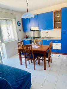 a kitchen with blue cabinets and a wooden table and chairs at Casa Sea view Blu Marettimo in Marettimo +41 photos
