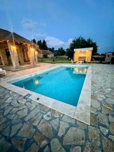 a swimming pool in a yard with a stone patio at Čajića avlija pool house in Obrenovac