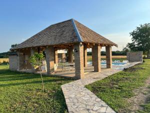 a wooden gazebo with a pool in a field at Čajića avlija pool house in Obrenovac +17 photos