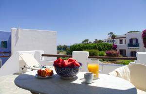 a table with a bowl of fruit and a glass of orange juice at Nefeli Hotel Leros in Agia Marina