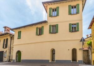 a yellow building with green shuttered windows at La Corte Del Lario - Contrada Scoscesa in Varenna
