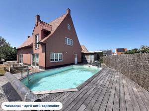 a house with a swimming pool on a wooden deck at Villa Charme - Koksijde in Koksijde