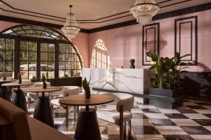 ein Restaurant mit Tischen, Stühlen und Fenstern in der Unterkunft Mural Piraeus Hotel in Piräus